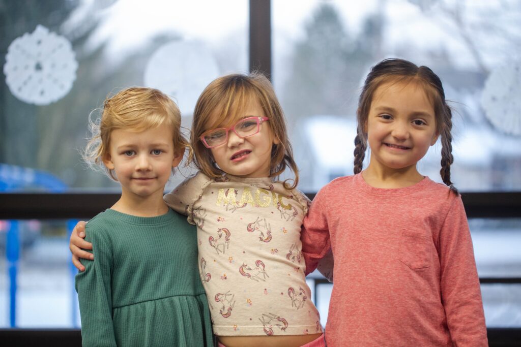 Bethel Community Education young girls smiling and standing together in a classroom at the Rockford, MI campus